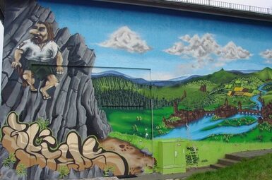Ein Graffiti in Wetzlar zeigt eine bunte Landschaft mit einem Riesen
