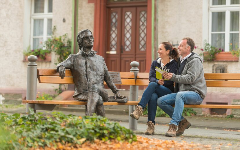 Wanderer sitzen neben der Goetheplastik auf der Bank