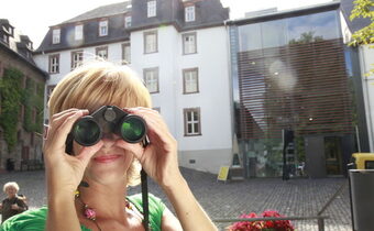 Touristin mit Fernglas im Deutschordenshof